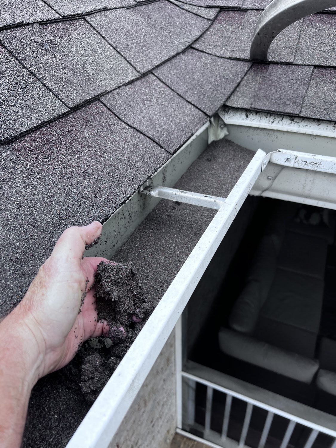 Hand pulling built-up muck from a gutter