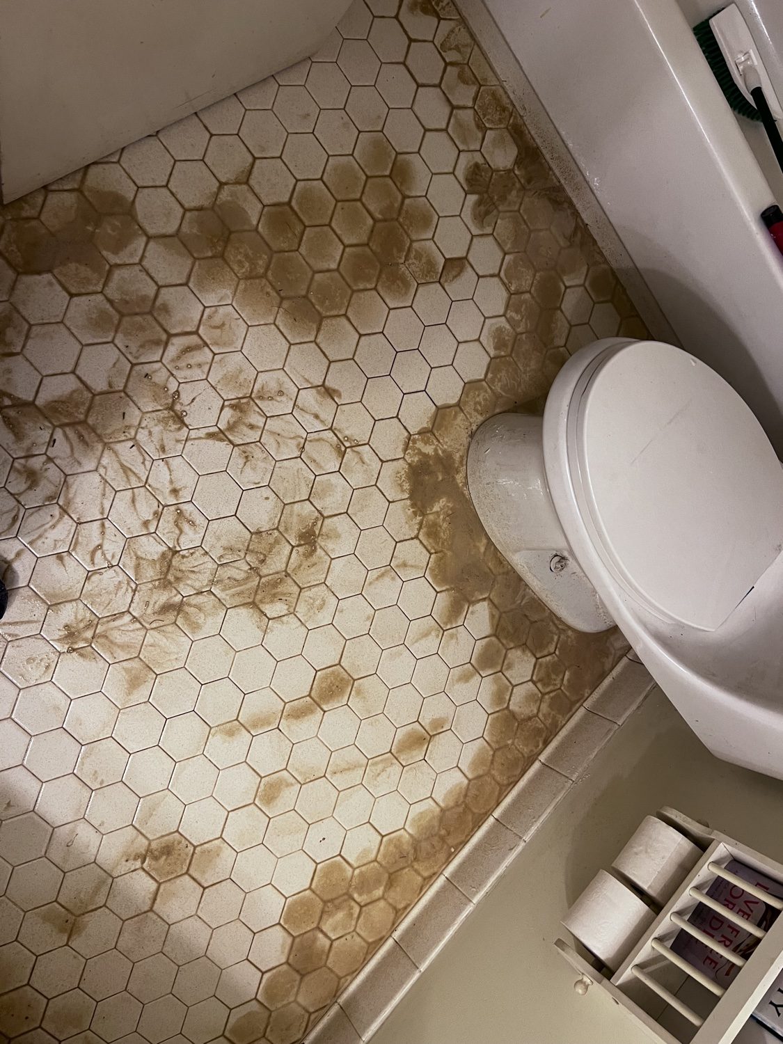Stained bathroom tile floor before deep cleaning